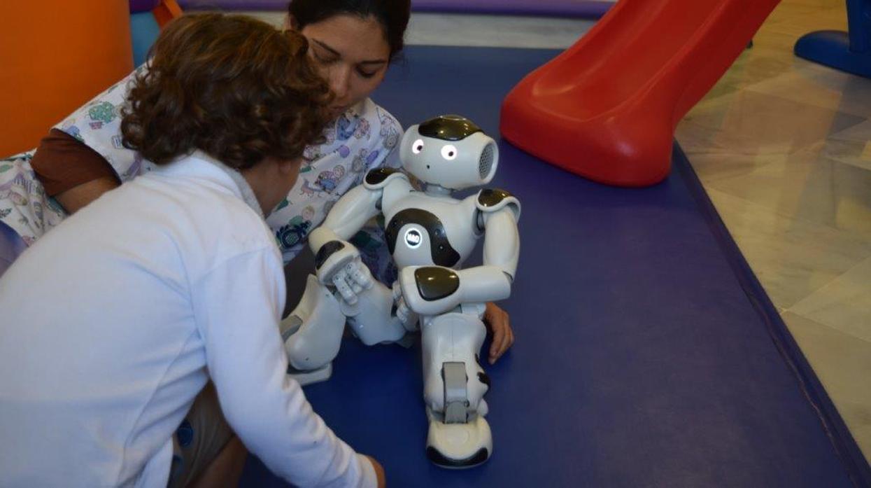 Un niño con problemas neuromotores junto al robot JuanDe en el Hospital de San Juan de Dios de Sevilla