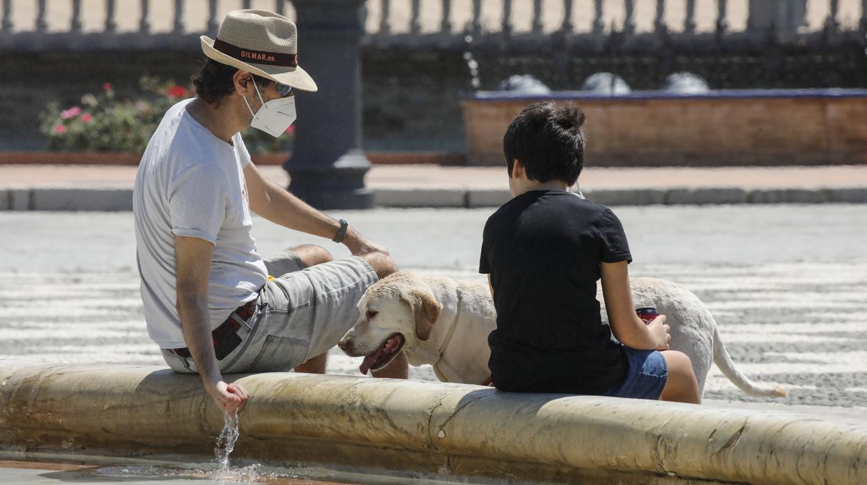 Dos personas se refrescan en una fuente de Sevilla por las altas temperaturas