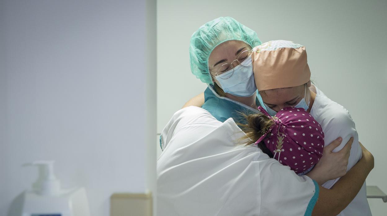 Tres enfermeras se abrazan por el traslado a planta del último paciente ingresado en la UCI del Sagrado Corazón