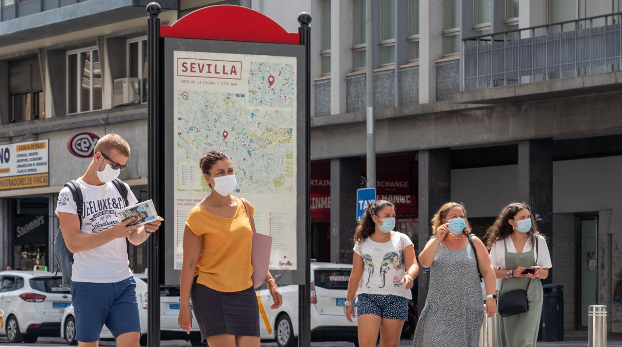 Varios turistas con mascarillas pasean por las calles de Sevilla