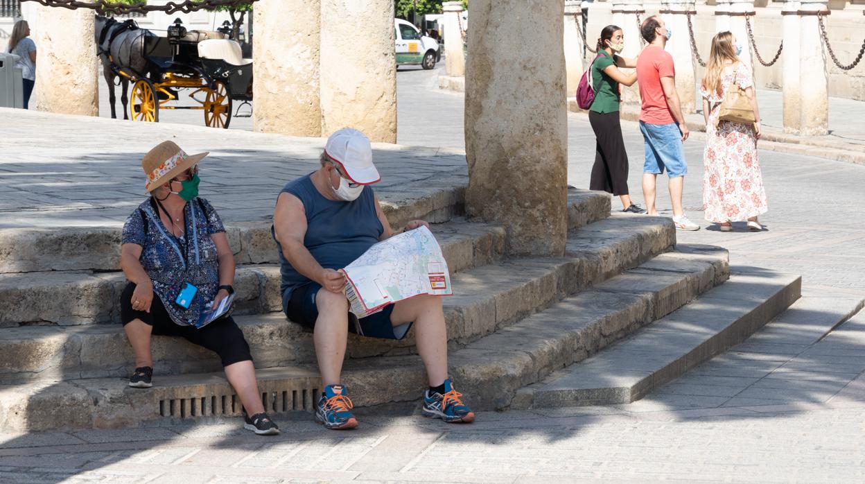 Unos turistas en los alrededores de la Catedral de Sevilla se toman un descanso