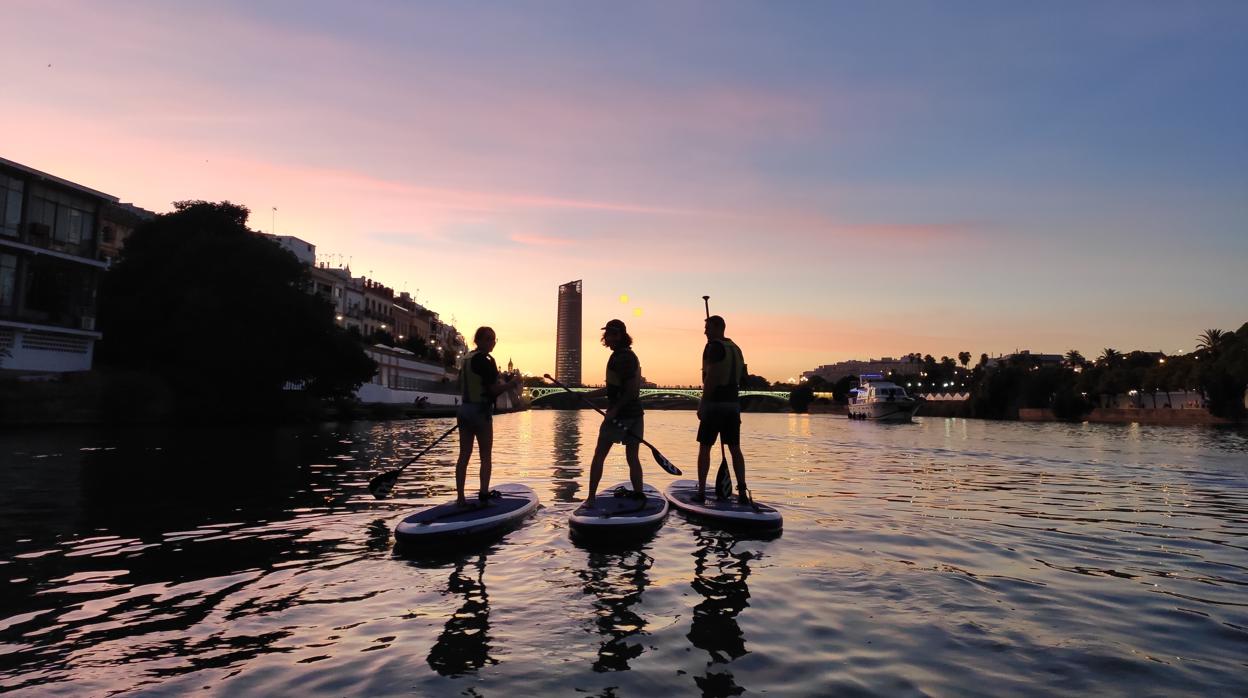 Tres jóvenes practicando Paddle Surf en el Guadalquivir