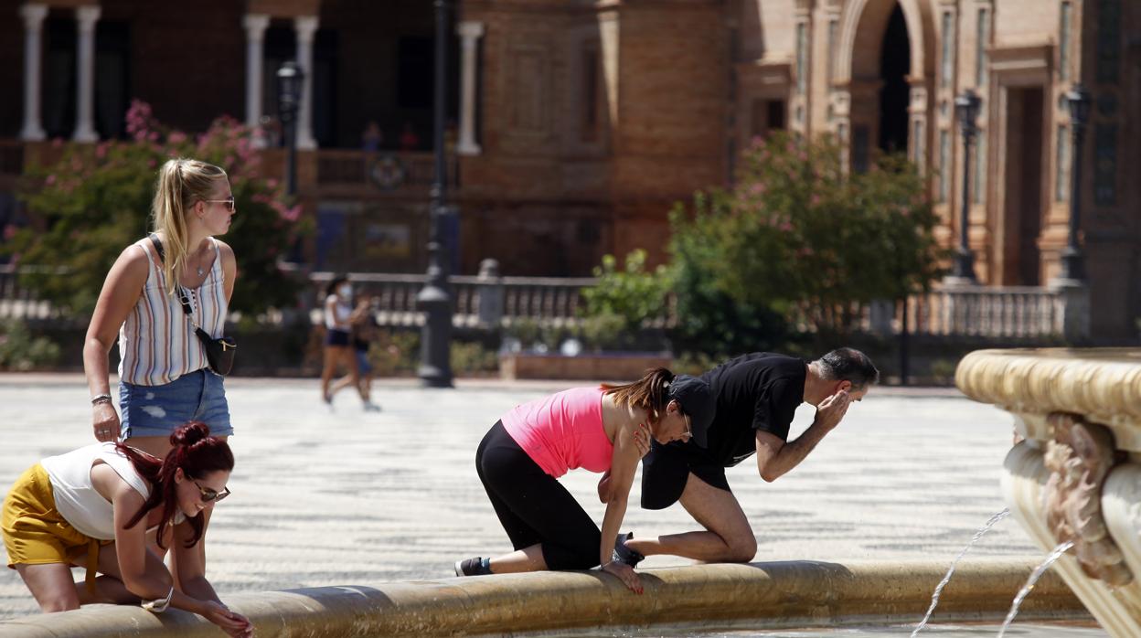 Varias personas se refrescan en la fuente de la Plaza de España