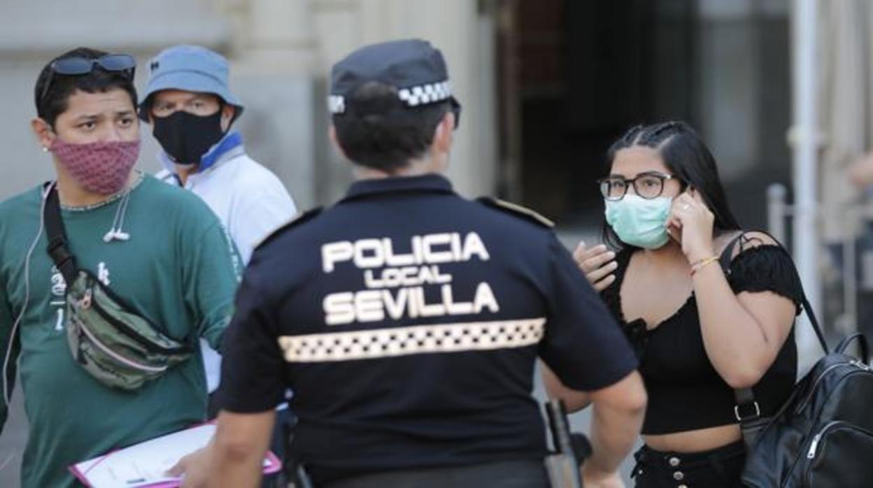 Un agente de la Policía Local de Sevilla atiende a unos turistas