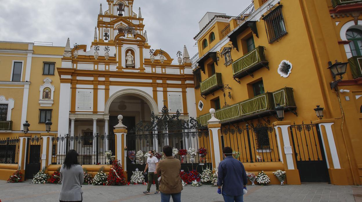 Devotos de la Macarena dejando ramos de flores y ofrendas a las puertas de la Basílica el Jueves Santo de 2020