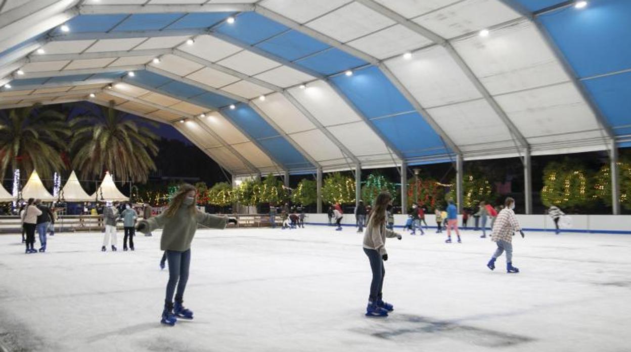 Varias personas patinan sobre hielo en una pista situada al lado del río Guadalquivir