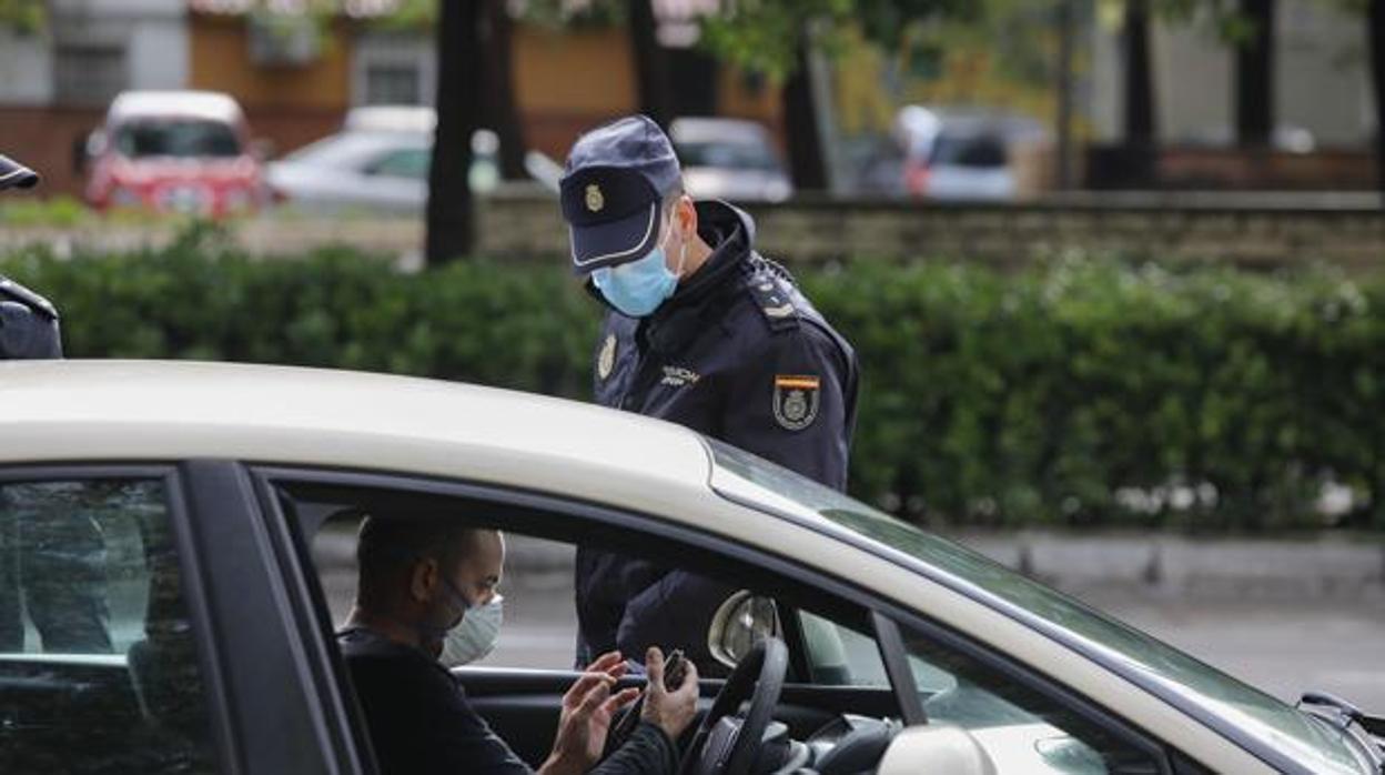 Un policía identifica a un conductor en Sevilla protegido con mascarillas para protegerse del coronaviru