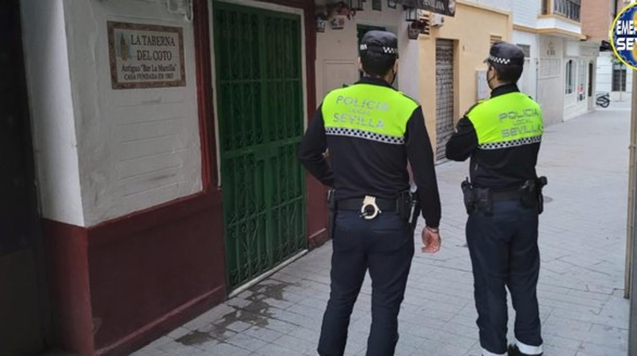 Dos agentes de la Policía Local junto al local denunciado de la calle Huelva