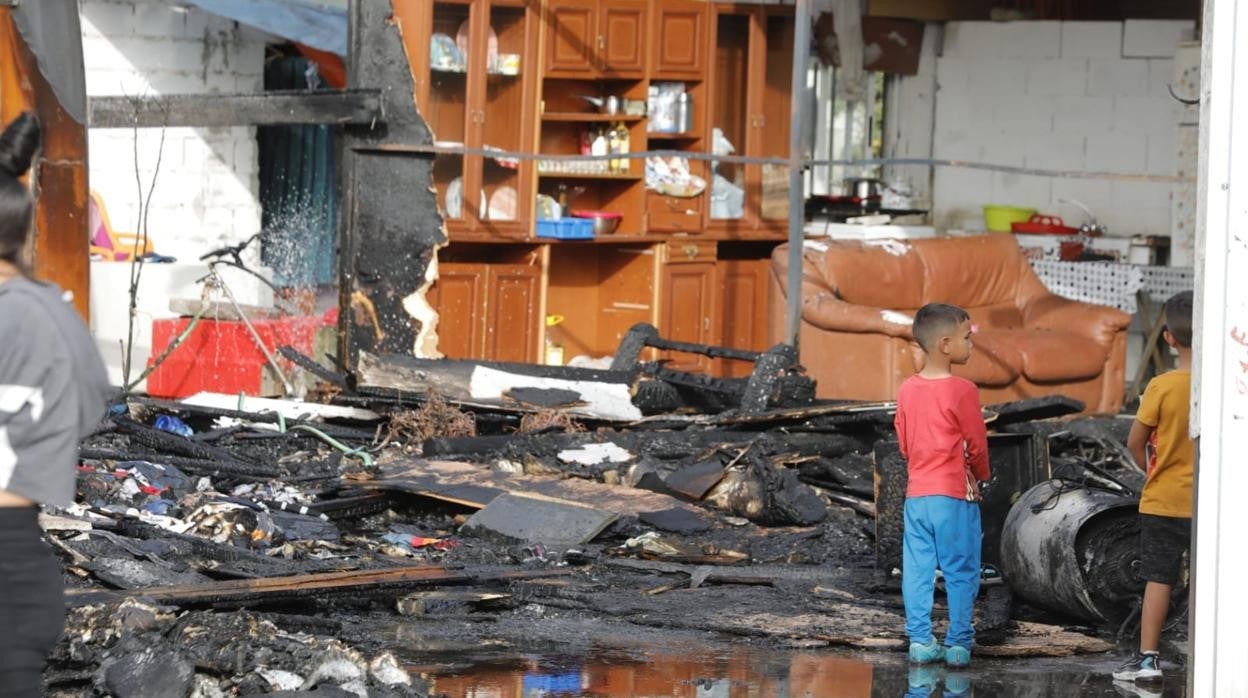 Dos niños junto a los restos de la chabola incendiada