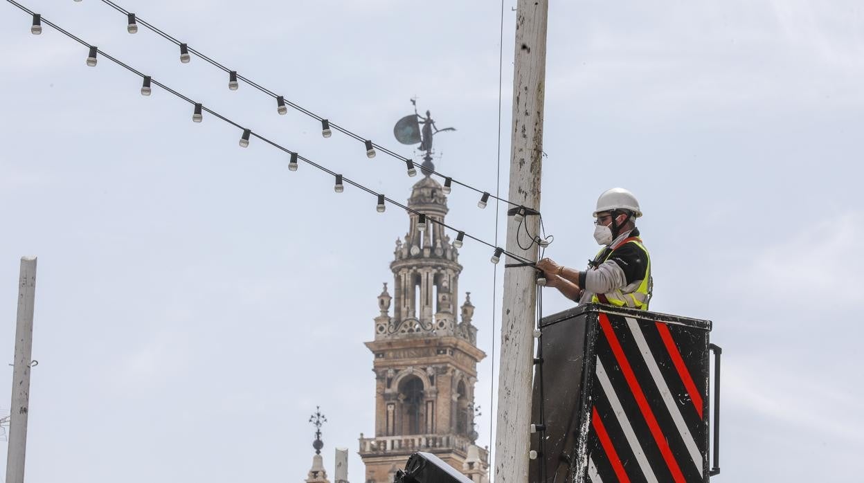 Un operario monta las luces de Feria en la plaza de San Francisco