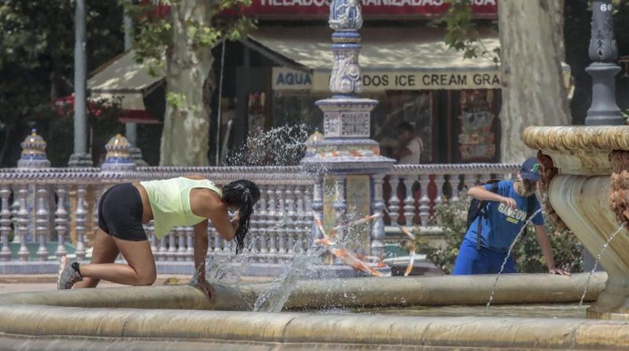 Dos personas se refrescan en una fuente del parque de María Luisa de Sevilla