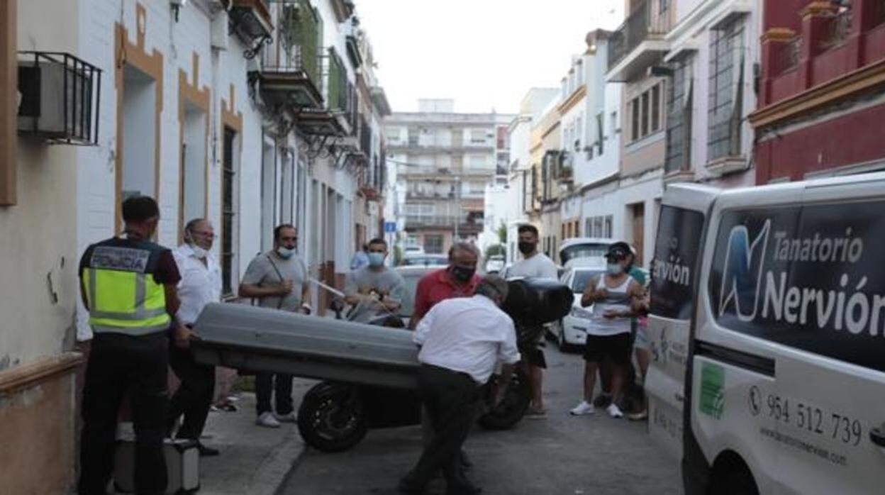 Los trabajadores de la funeraria sacan el cuerpo de la víctima de la vivienda
