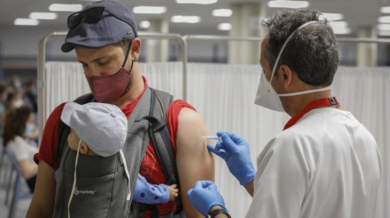 Un padre junto a su hijo recibiendo una dosis de la vacuna en Sevilla