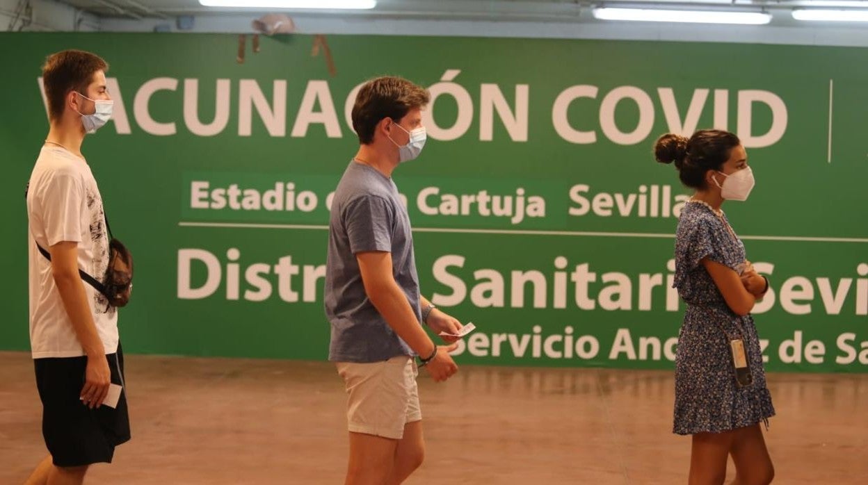 Tres jóvenes aguardan su turno para recibir la vacuna en el estadio de la Cartuja