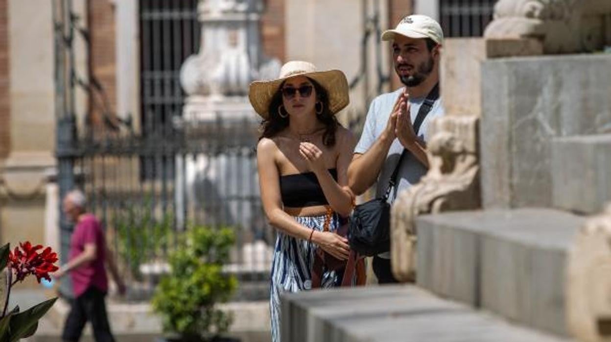 Dos turistas pasean por la Plaza del Triunfo de Sevilla en un caluroso día de verano