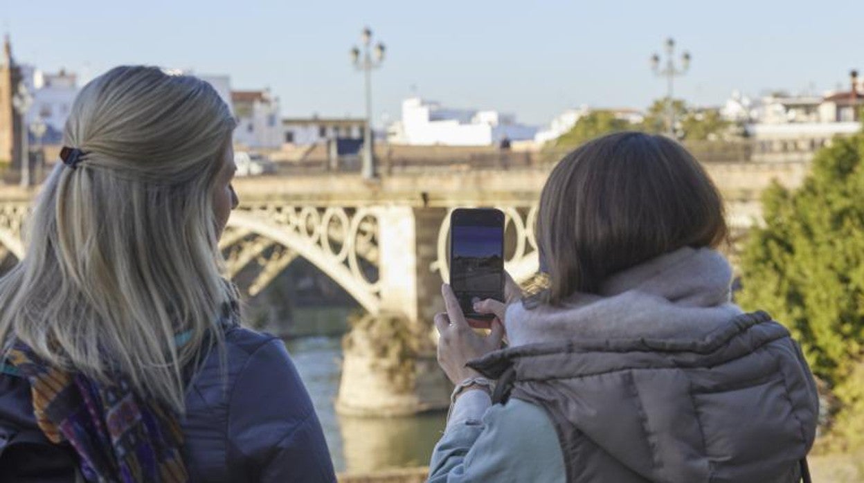 Dos turistas hacen una foto del puente del Triana