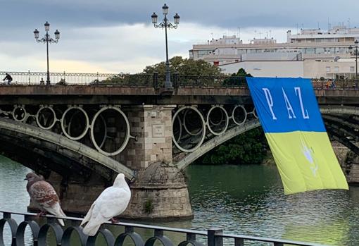 Una bandera de Ucrania luce sobre el puente de Triana para pedir la paz