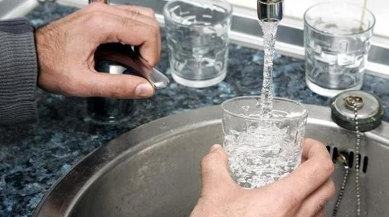 Una persona llena un vaso de agua potable de un grifo en un domicilio familiar