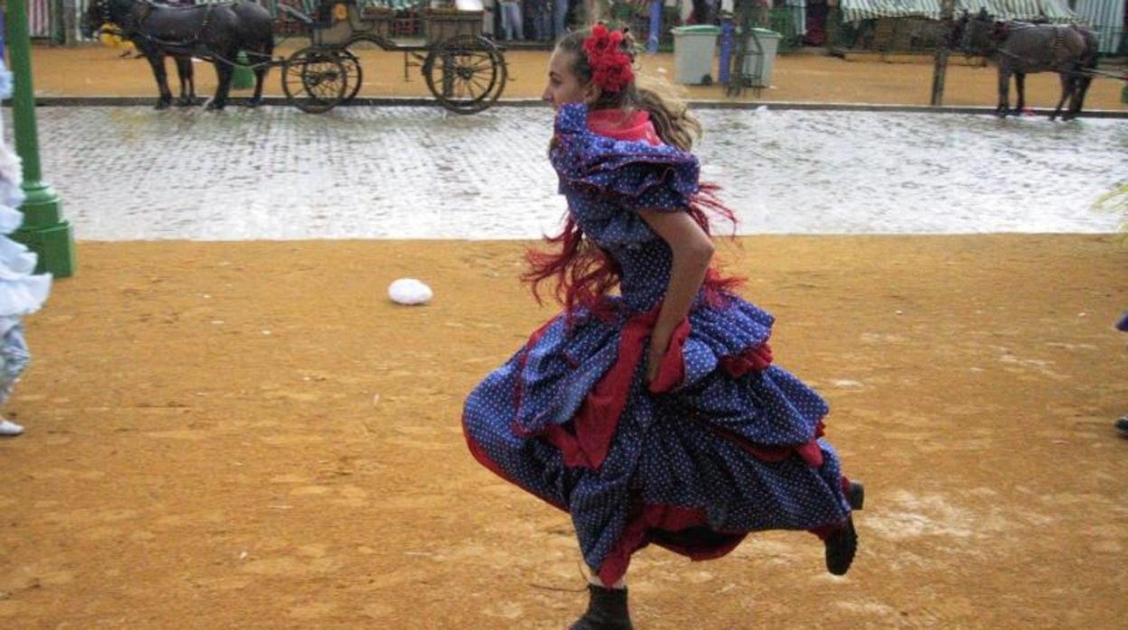 Una joven vestida de flamenca durante un día de lluvia en el real