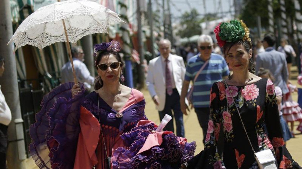 Dos mujeres vestidas de flamenca en una calurosa jornada en el real de la feria