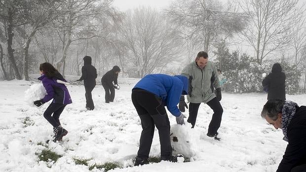 Unos turistas se divierten con la nieve en O Cebreiro (Lugo), donde la temperatura ha bajado bruscamente y se ha producido la primera nevada de la temporada