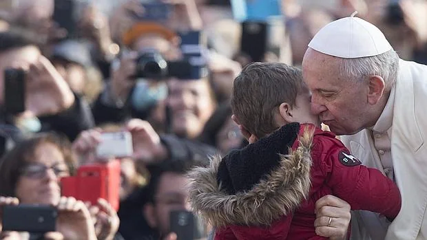 El Papa Francisco besa a un niño a su llegada hoy la plaza de San Pedro del Vaticano para presidir la audiencia general de los miércoles