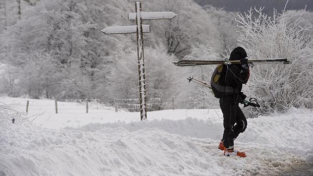 Un esquiador carga con sus esquís camino de las pistas