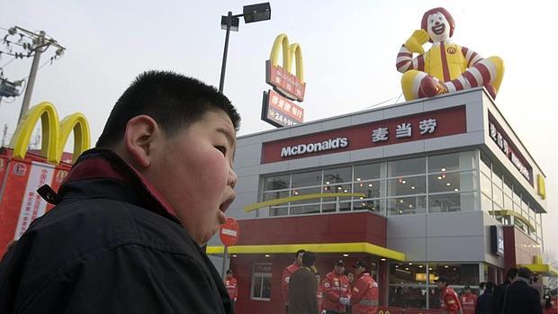 Un niño en Pekín, frente a un establecimiento de comida rápida