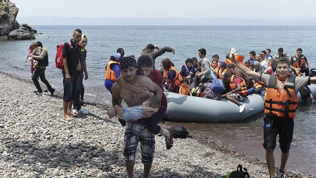 Un refugiado iraquí que lleva en brazos a su bebé y a su mujer ciega agarrada a su espalda, a su llegada, este pasado lunes 27 de junio, en lancha a la costa nororiental de la isla de Lesbos (Grecia)