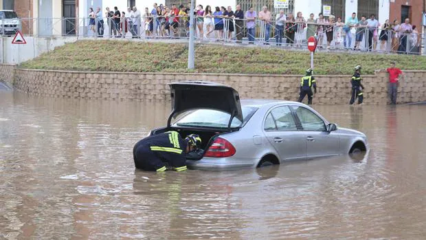 Un bombero junto a un vehículo que ha quedado atrapado por la inundación causada por la fuerte tomenta registrada esta tarde en el término municipal de Villanueva de la Serena (Badajoz)