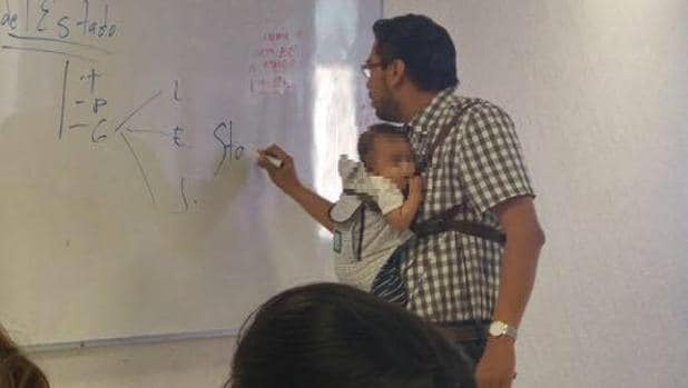 El profesor Moisés Reyes sostiene al bebé de una alumna durante la clase