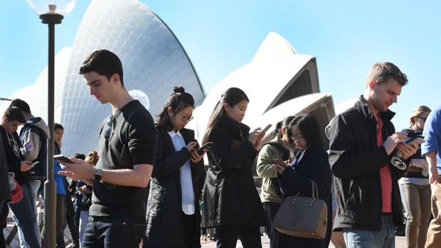 Jóvenes reunidos frenta a la ópera de Sidney jugando al Pokémon GO