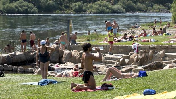 Varias personas disfrutan de las altas temperaturas en la zona fluvial del río Miño y las termas de A Chavasqueira