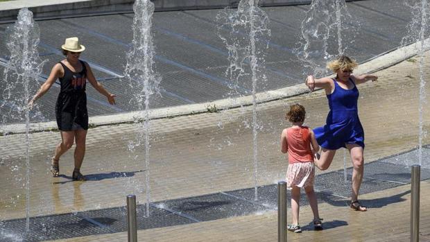 Varias personas disfrutan en una fuente de Bilbao para intentar mitigar las altas temperaturas