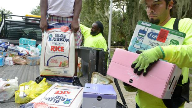El voluntario José Martinez (d), residente del área de la Pequeña Haití en la ciudad de Miami (Florida), colabora con otros compañeros en el acopio de alimentos, ropa y agua para enviar a Haití, como parte de la ayuda solidaria a ese país