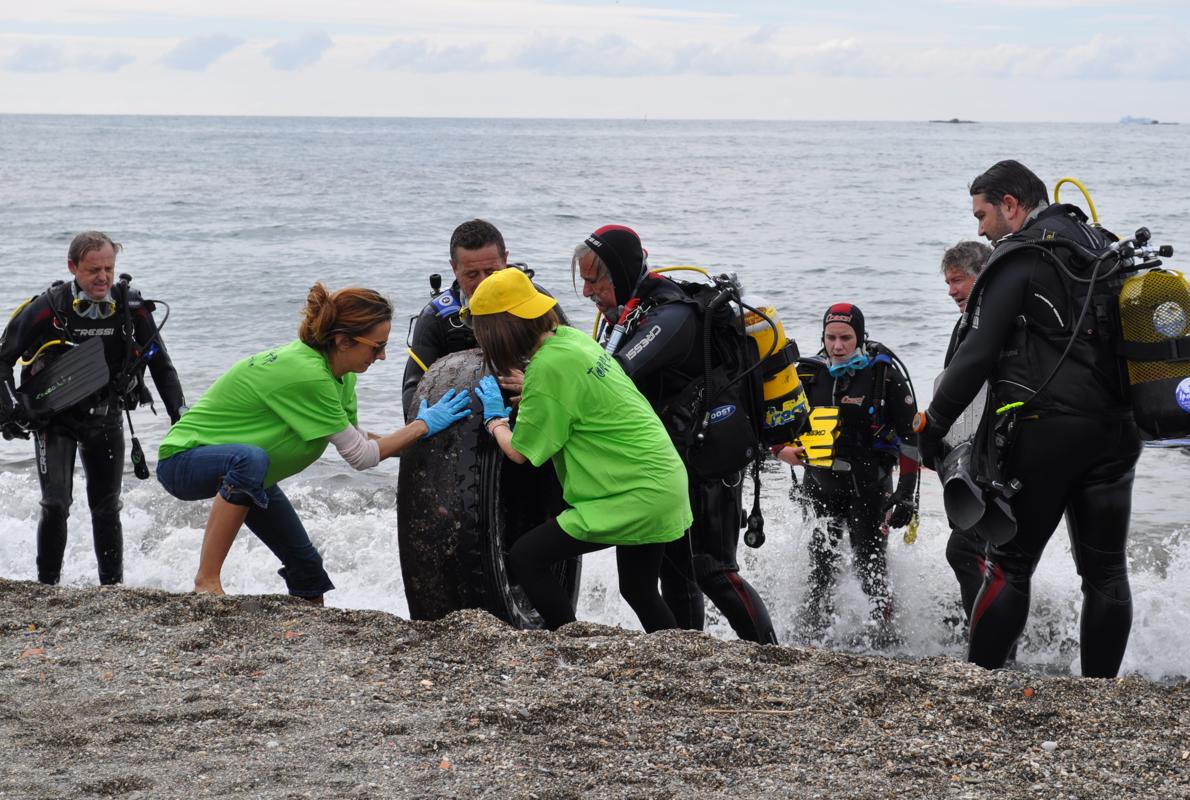 Buceadores y voluntarios sacan un neumático del fondo del mar