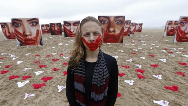 Una voluntaria de la ONG Río de Paz posa en la playa de Copacabana, junto a imágenes de modelos que representan a mujeres que sufrieron algún tipo de abuso sexual
