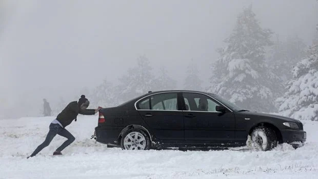 Un hombre empuja un vehículo atrapado en la nieve en el Alto del Perdón (Navarra)