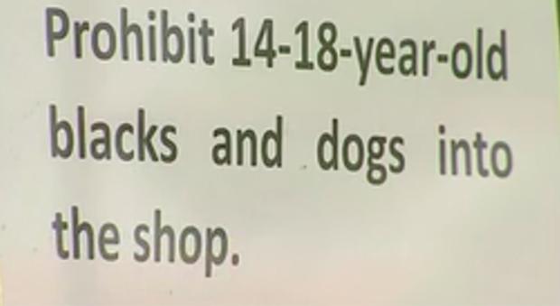 El cartel colocado en el escaparate de la tienda prohíbe la entrada de perros y jóvenes negros