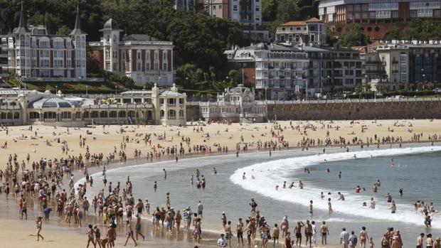 Numerosos visitantes pasean por la playa de La Concha de San Sebastián, donde el jueves se alcanzaron los 30º