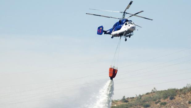 Un helicóptero trabaja para controlar el fuego declarado en Málaga