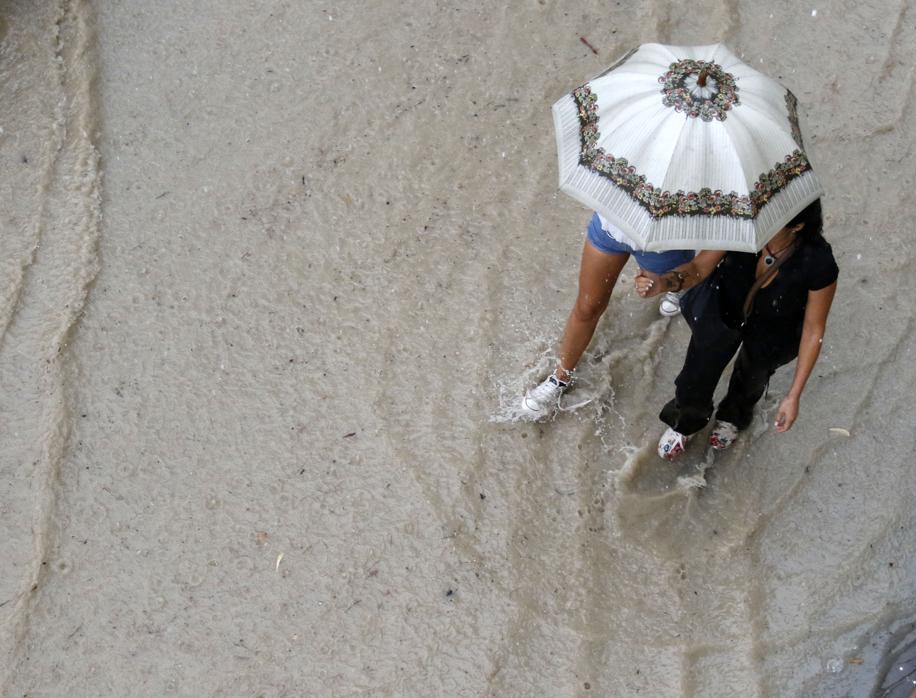 Dos mujeres caminan por la calle en plena inundación