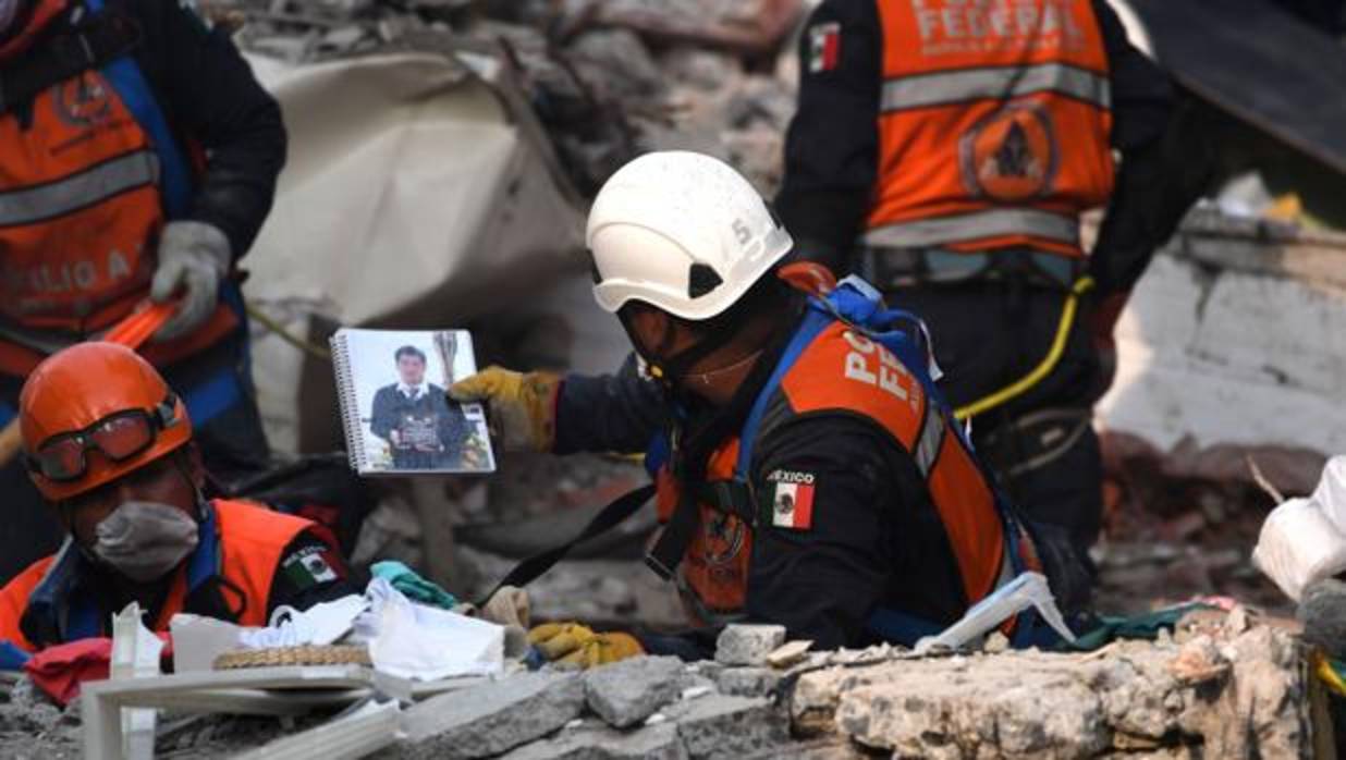 Un trabajador recupera objetos personales de debajo de los escombros de un edificio derruido