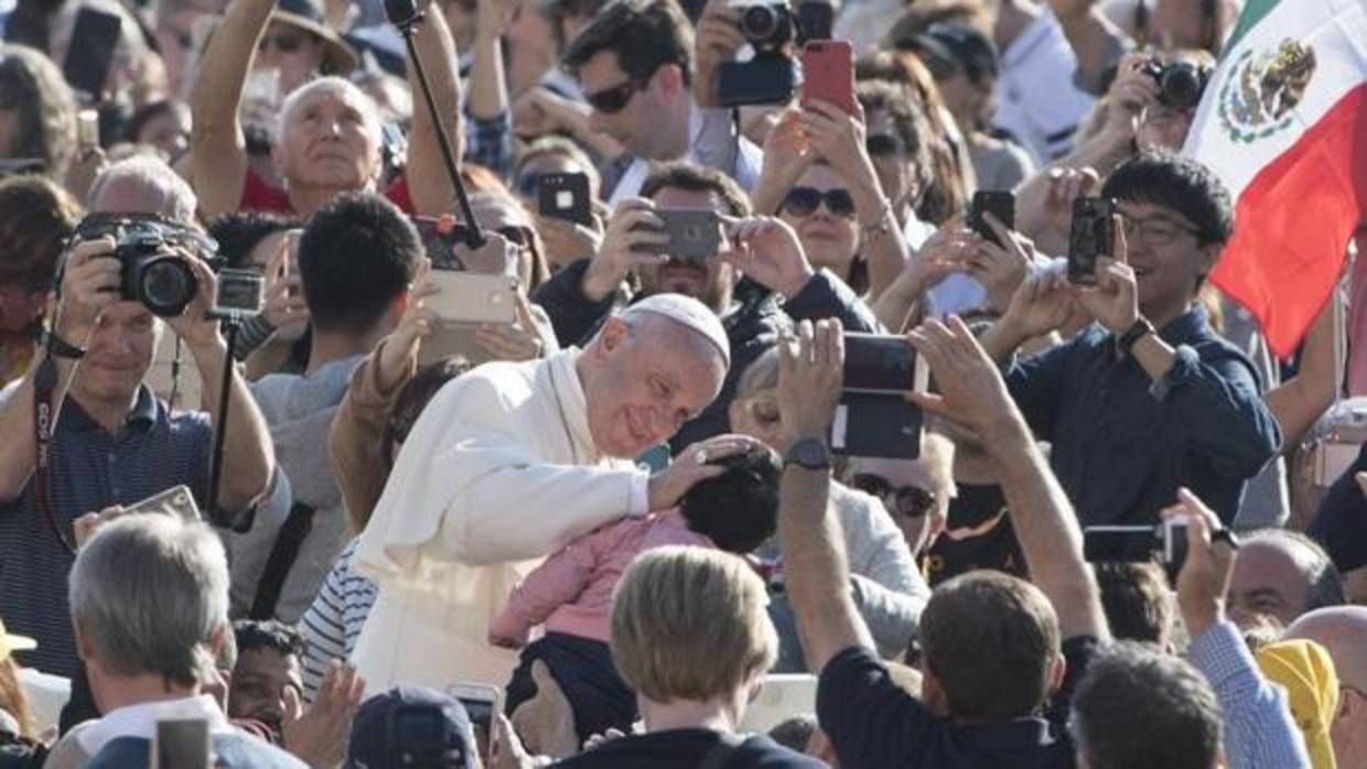 El Papa bendice a un bebé a su llegada a su audiencia general de los miércoles en la plaza de San Pedro