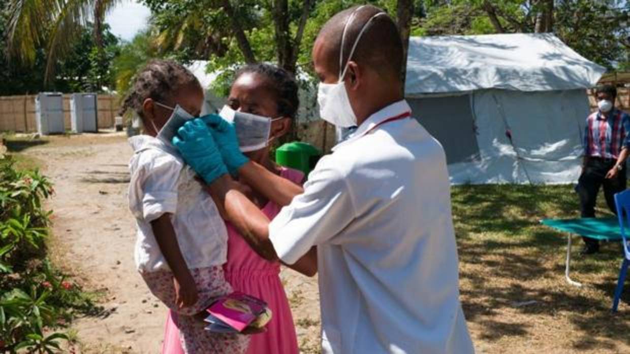 Un médico coloca una mascarilla a una niña en un centro de Toamasina (Madagascar)
