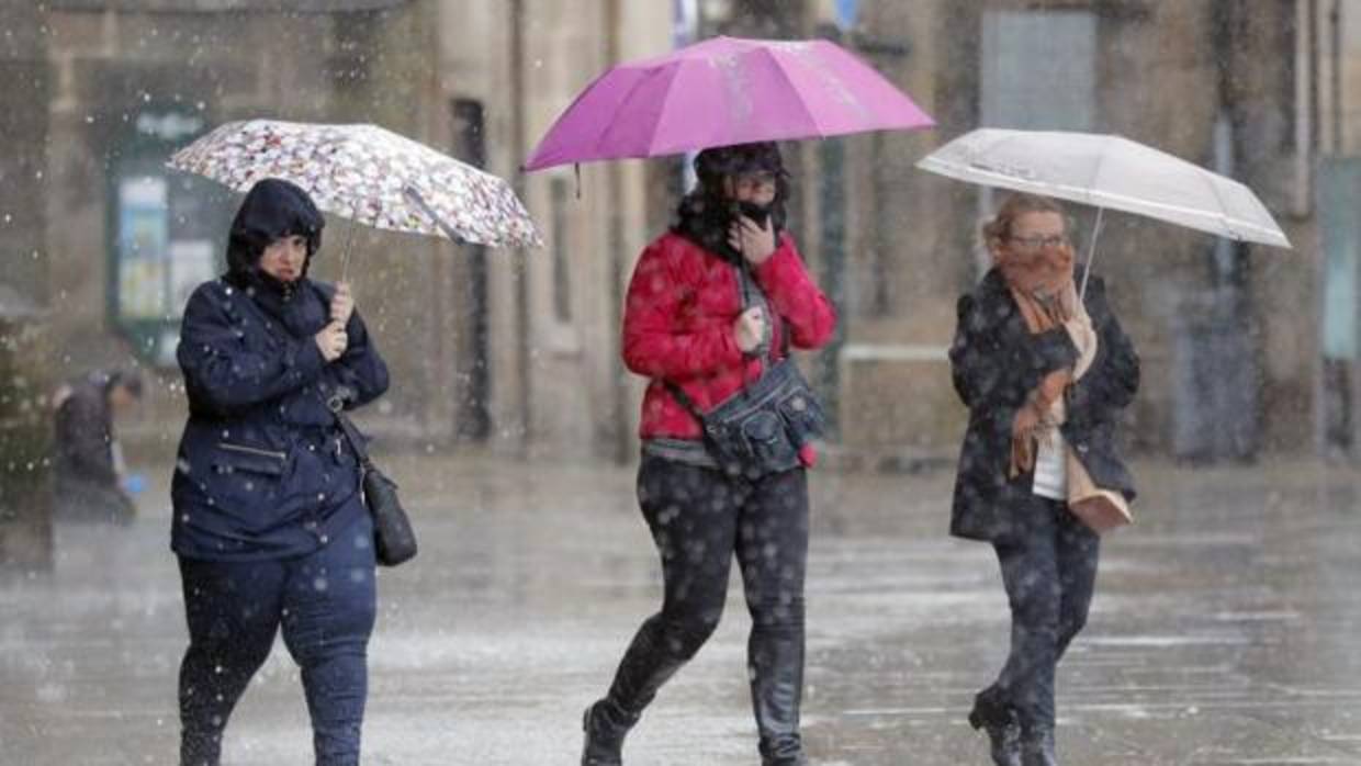 Varias personas transitan bajo la lluvia la plaza del Obradoiro, en Santiago de Compostela