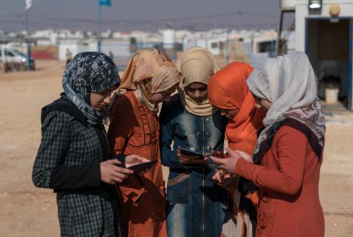 Un grupo de adolescentes sirias miran sus móviles y tabletas en un campo de refugiados
