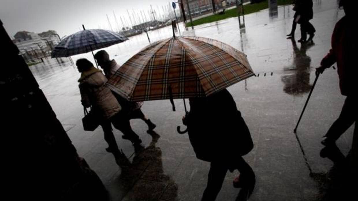 Varias personas caminan bajo la lluvia por una céntrica calle de A Coruña