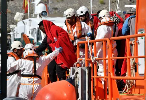 Un grupo de trabajadores de Salvamento Marítimo auxiliando a un grupo de inmigrantes