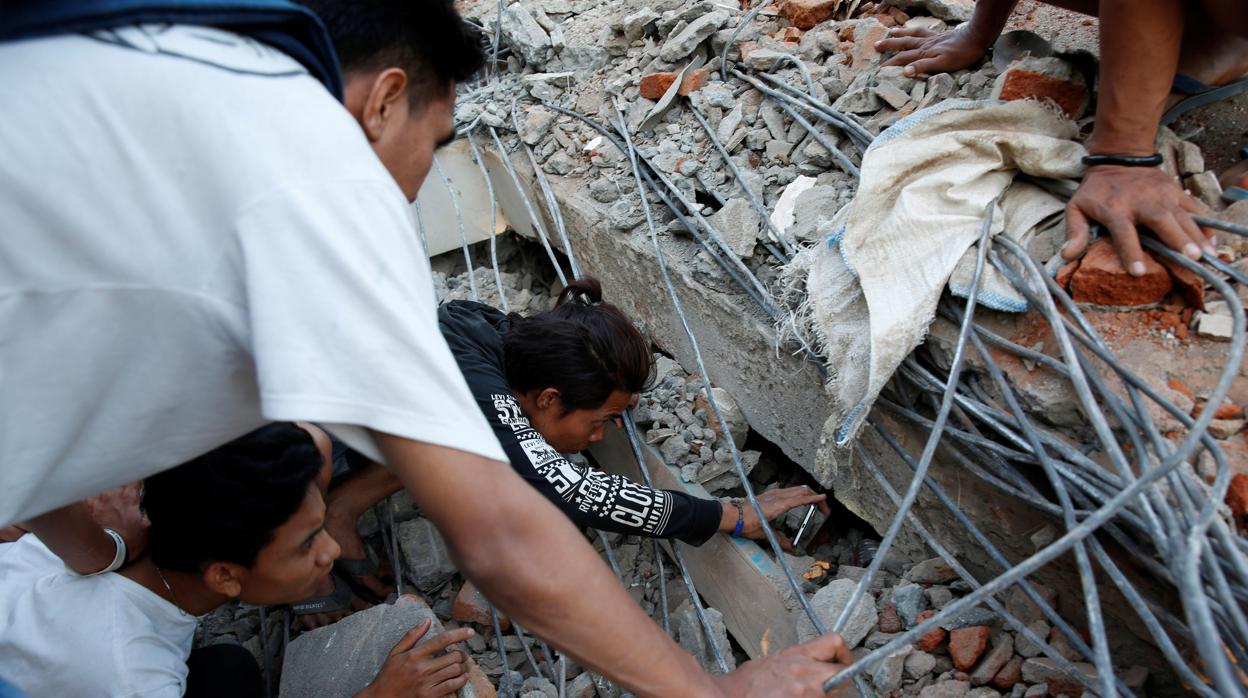 Ciudadanos de Lombok buscando posibles supervivientes entre los escombros